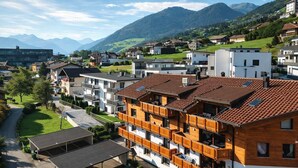 Un quartier résidentiel avec des immeubles modernes, un parking couvert et une vue sur les montagnes en arrière-plan.