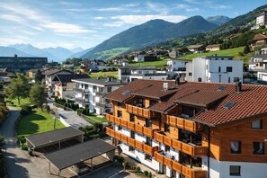 Un quartier résidentiel avec des immeubles modernes, un parking couvert et une vue sur les montagnes en arrière-plan.