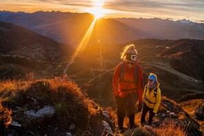 Paisatge montanós amb una persona i un nen al cim durant el capvespre.