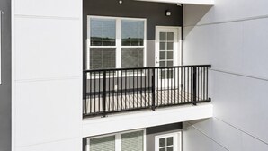 Un immeuble à plusieurs étages doté d’un balcon orné d’une rambarde en métal noir.