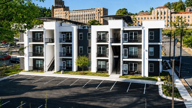 Een meerlaags woongebouw met een parkeerplaats ervoor.