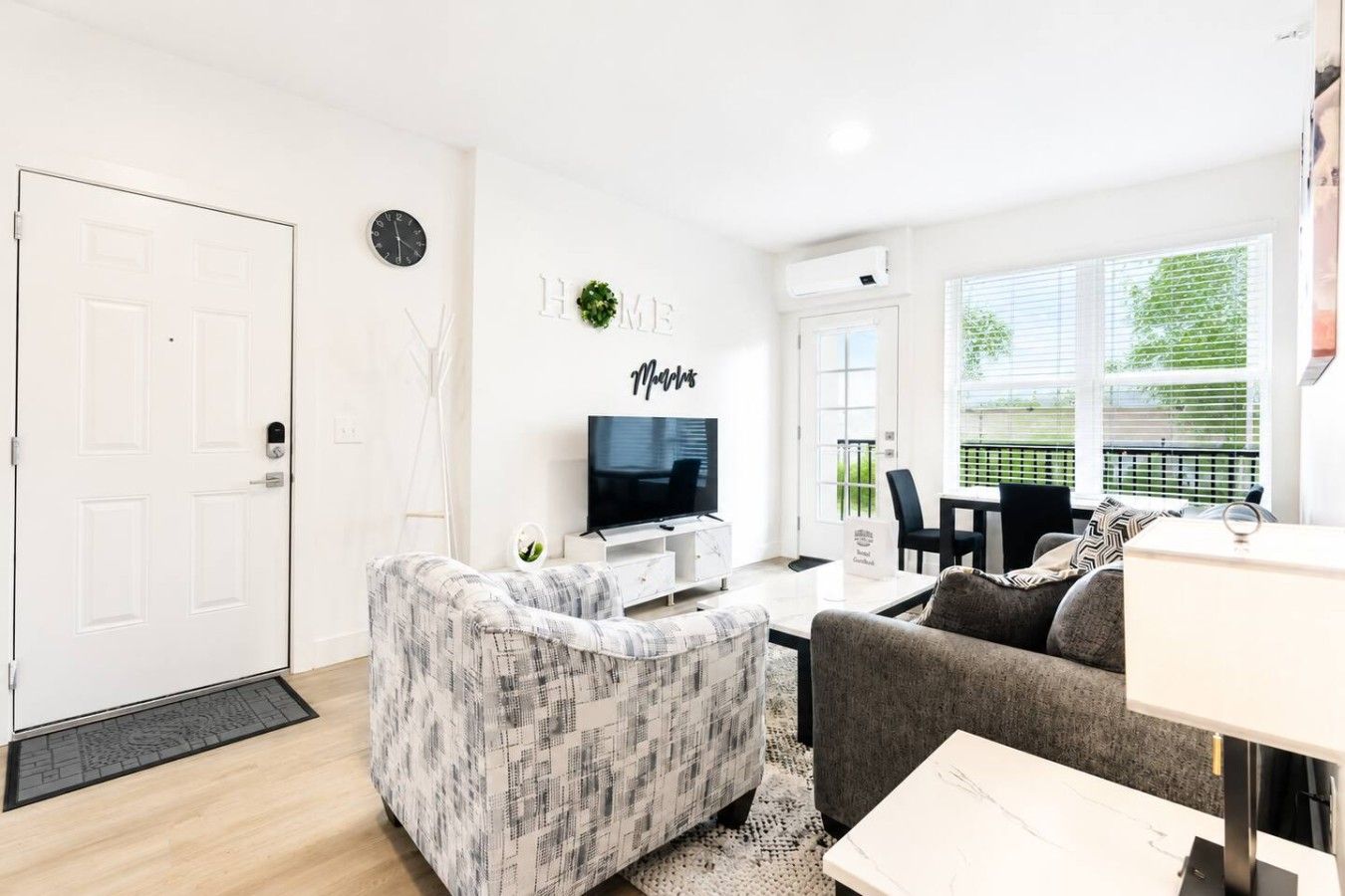 A modern living room with a television, a sofa, a coffee table, and a dining area with a table and chairs.