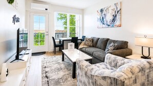 Un salon moderne avec un canapé, une table basse, un téléviseur et un tableau accroché au mur.