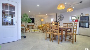 A spacious kitchen with modern appliances, a dining area with wooden chairs, and a stone accent wall.
