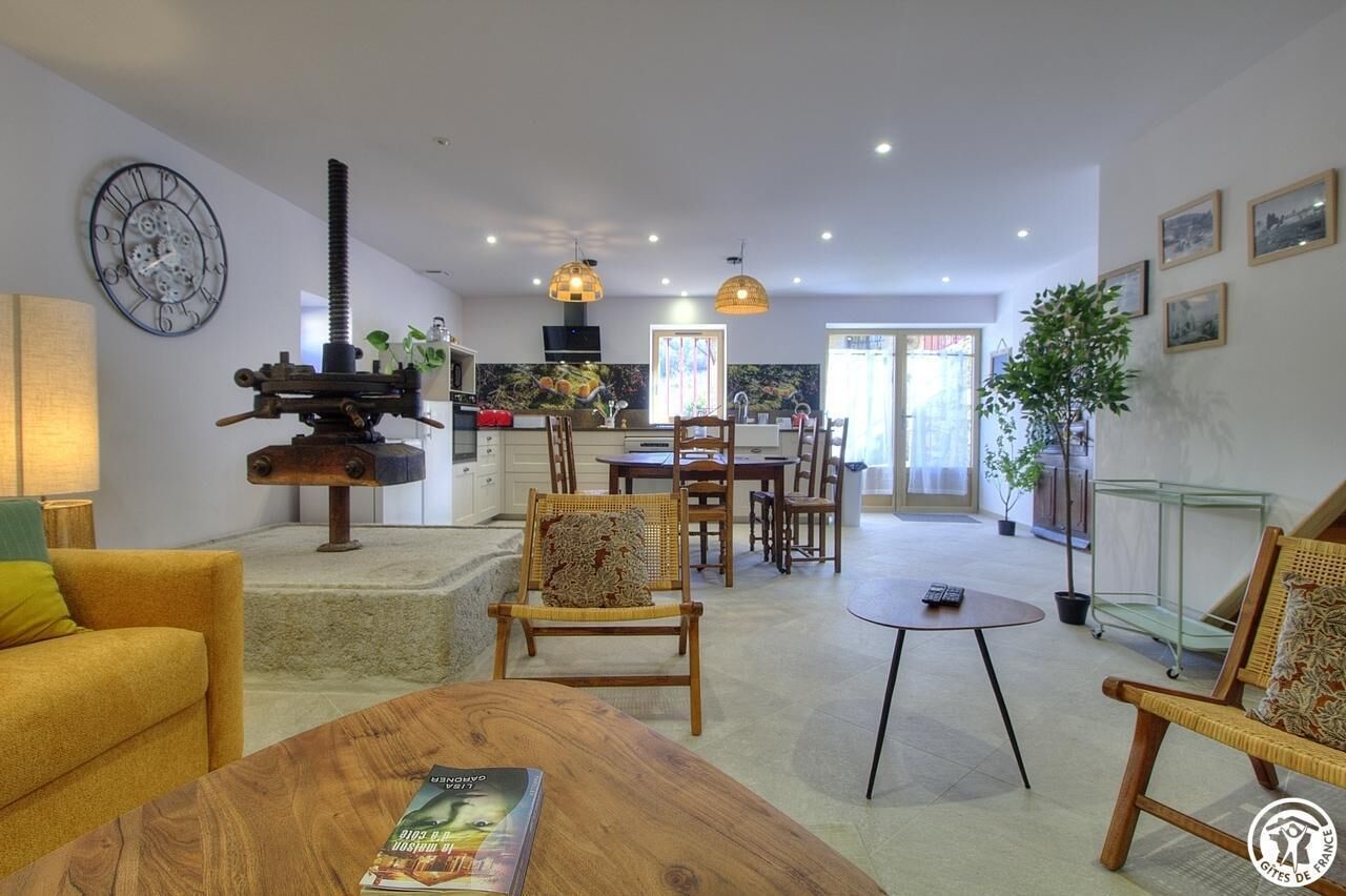 A modern living room with a wooden coffee table, a sofa, and a dining area with chairs and a table.