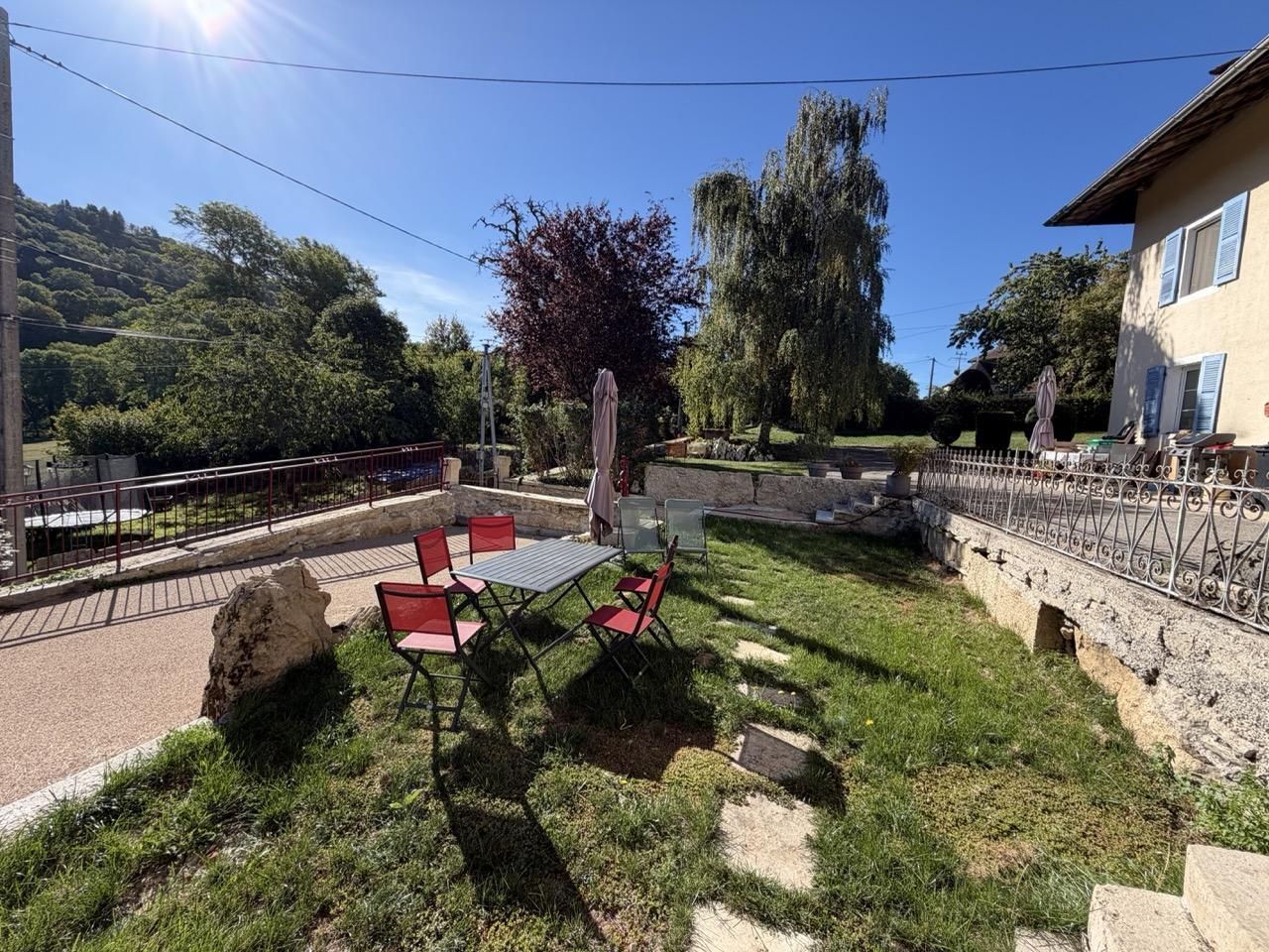 A patio with a table and chairs, surrounded by a stone wall and a metal fence.