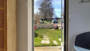 A room with a wooden wardrobe, a blue chair, and a view of a garden through a glass door.