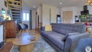 A modern living room with a grey sofa, wooden coffee table, and a staircase leading to an upper level.