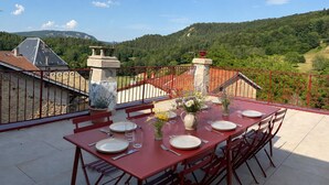 A dining table set outdoors with a view of a mountainous landscape.