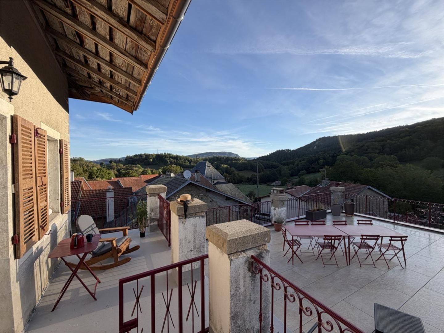 A terrace with a view of a valley, a table and chairs, and a rocking chair.