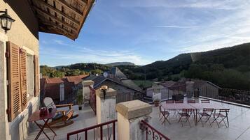 A terrace with a view of a valley, a table and chairs, and a rocking chair.