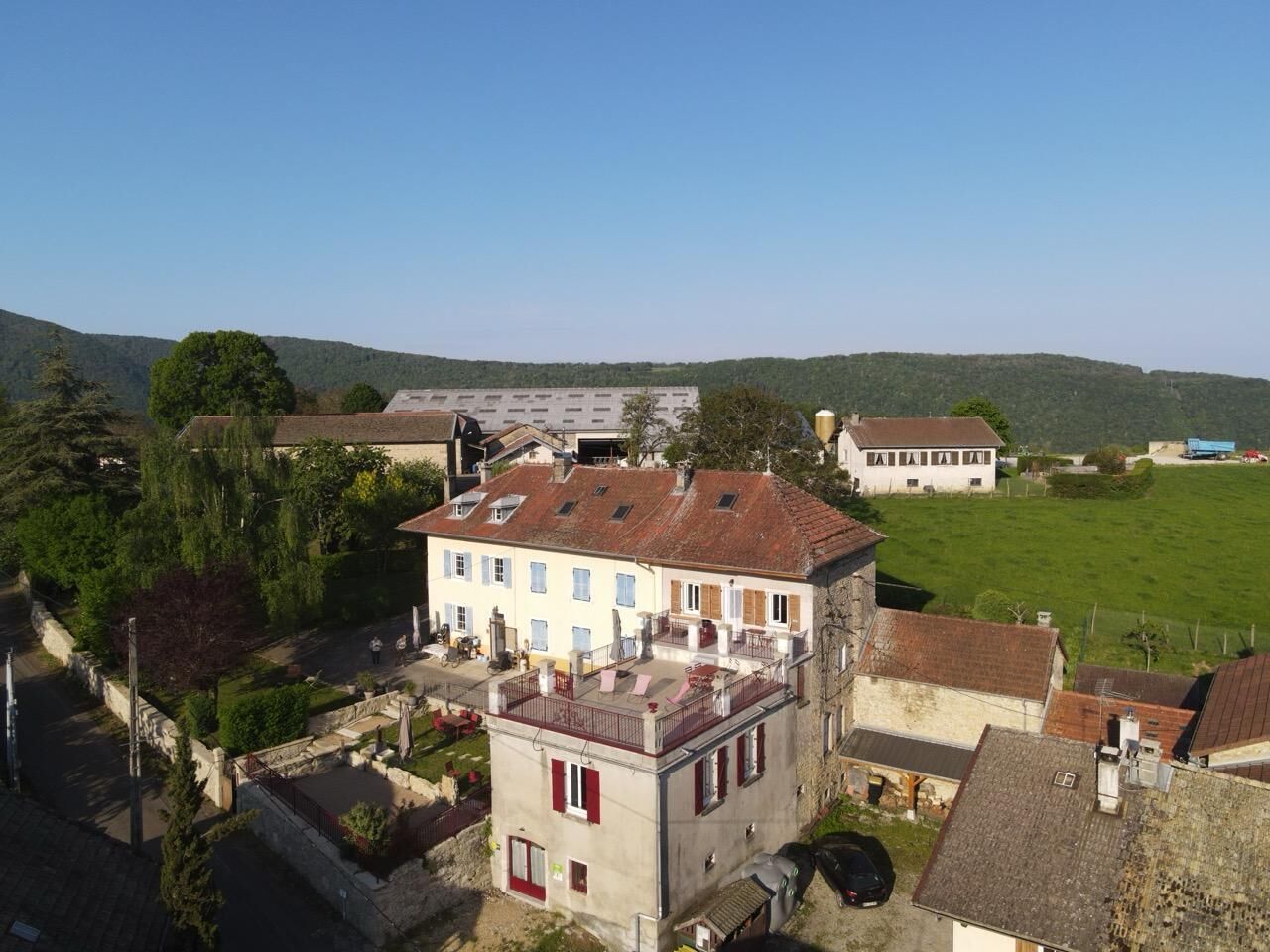 Ein Wohngebiet mit einem zweistöckigen Haus mit Balkon, umgeben von Grünflächen und weiteren Gebäuden.