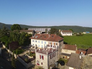 A residential area with a two-story house featuring a balcony, surrounded by greenery and other buildings. - Gîte d'Amédée - ARANDAS - Gîte (ARANDAS)