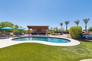 A pool area with a wooden pergola, lounge chairs, and umbrellas. - Spacious 5-bedroom house with Pickleball, Heated Pool, Hot Tub, and much more (Scottsdale)