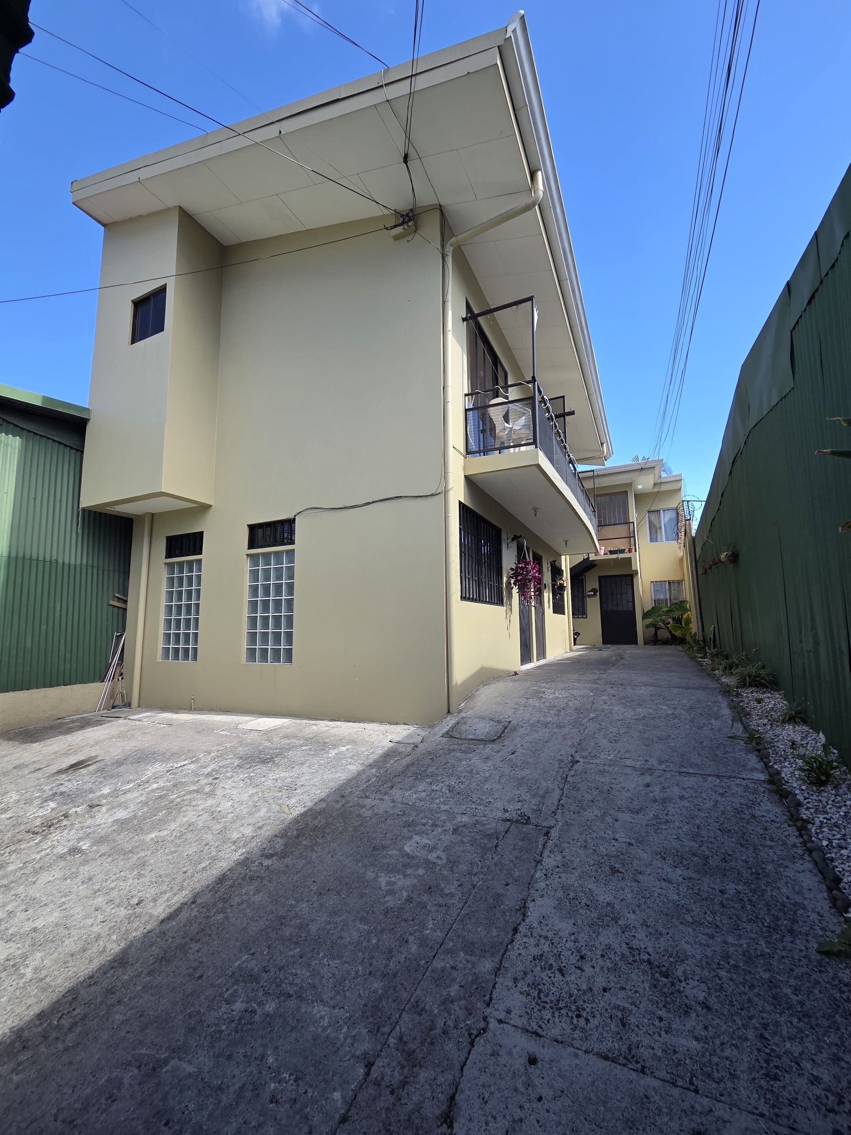 A two-story building with a flat roof and a balcony on the upper floor.