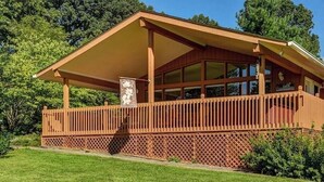 Una casa de madera con un porche cubierto y un patio cercado.