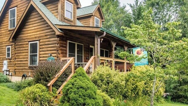 Eine Blockhütte mit Veranda und einer Treppe zum Eingang.