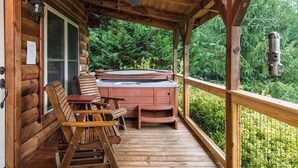 Eine Holzterrasse mit Whirlpool und zwei Holzstühlen.