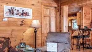 Ein Holzhütten-Interieur mit Essbereich, einer Couch, einer Lampe und einem gerahmten Bild an der Wand.