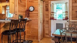 Ein Holzblockhaus-Interieur mit Küchenzeile, Esstisch und Stühlen.