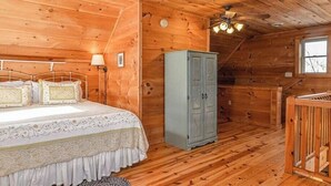 Ein Schlafzimmer in einer Holzhütte mit einem Bett, einem Kleiderschrank und einem Fenster.