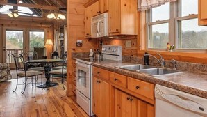 Una cocina tipo cabaña de madera con encimeras de granito, lavavajillas, estufa y pileta.