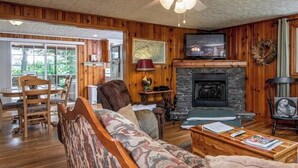 Un salon chaleureux avec une cheminée, des murs en bois et un coin salon confortable.