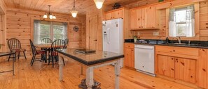 Ein Interieur einer Holzhütte mit Esstisch, Stühlen, einem Kühlschrank, einer Spüle und Holzschränken.