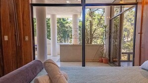 Een kamer met een bed, een groot raam en uitzicht op de omgeving.