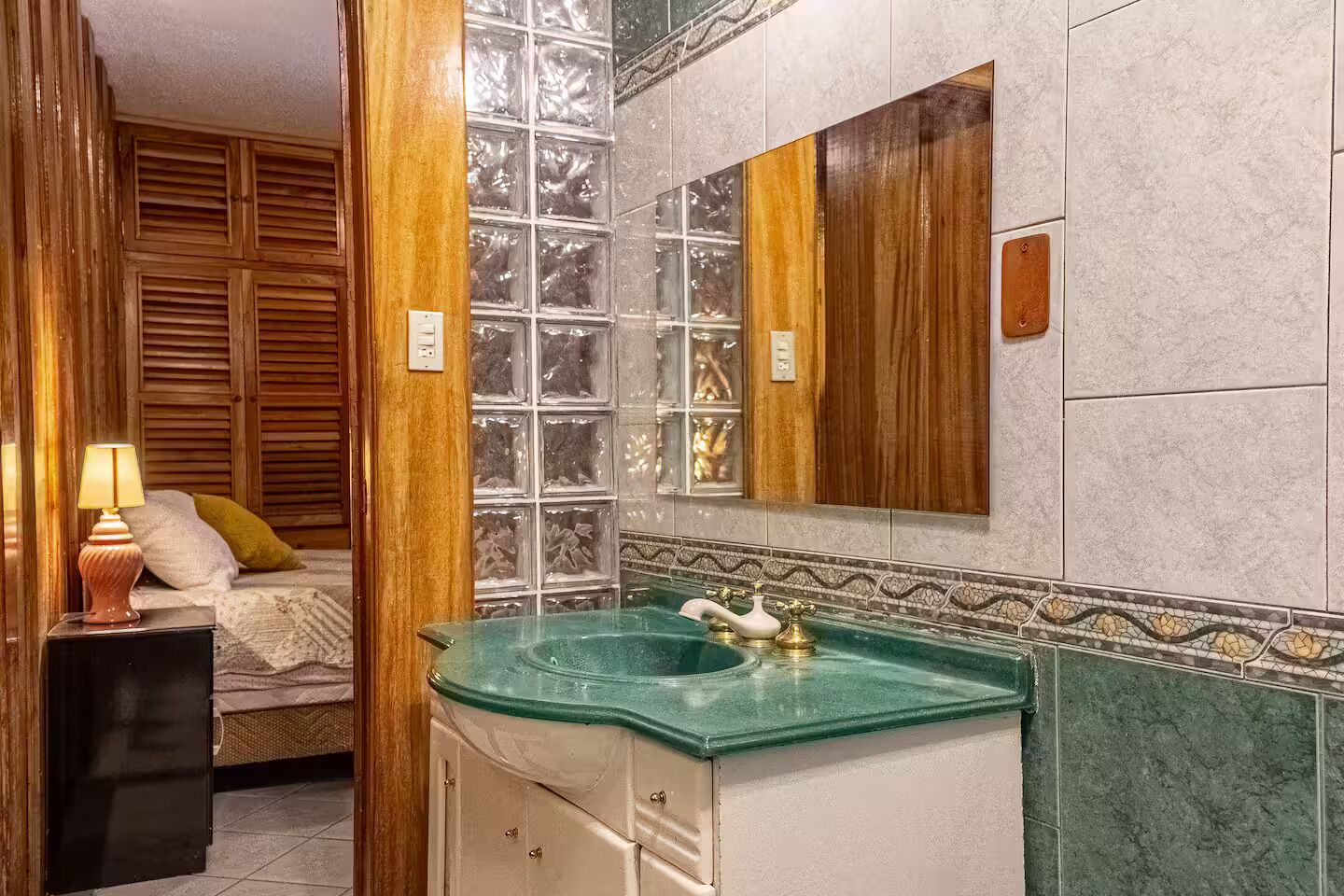 A bathroom with a glass sink, wooden cabinets, and a mirror.