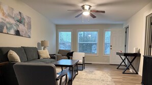 A living room with a sofa, chairs, a coffee table, a lamp, and a ceiling fan.