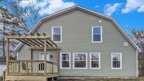 A two-story house with a wooden deck and a covered porch.