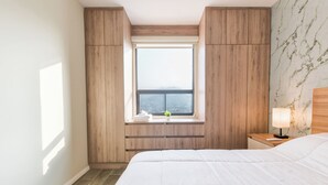 Een slaapkamer met een groot bed, een raam met uitzicht, houten lambrisering en een nachtkastje met lamp.