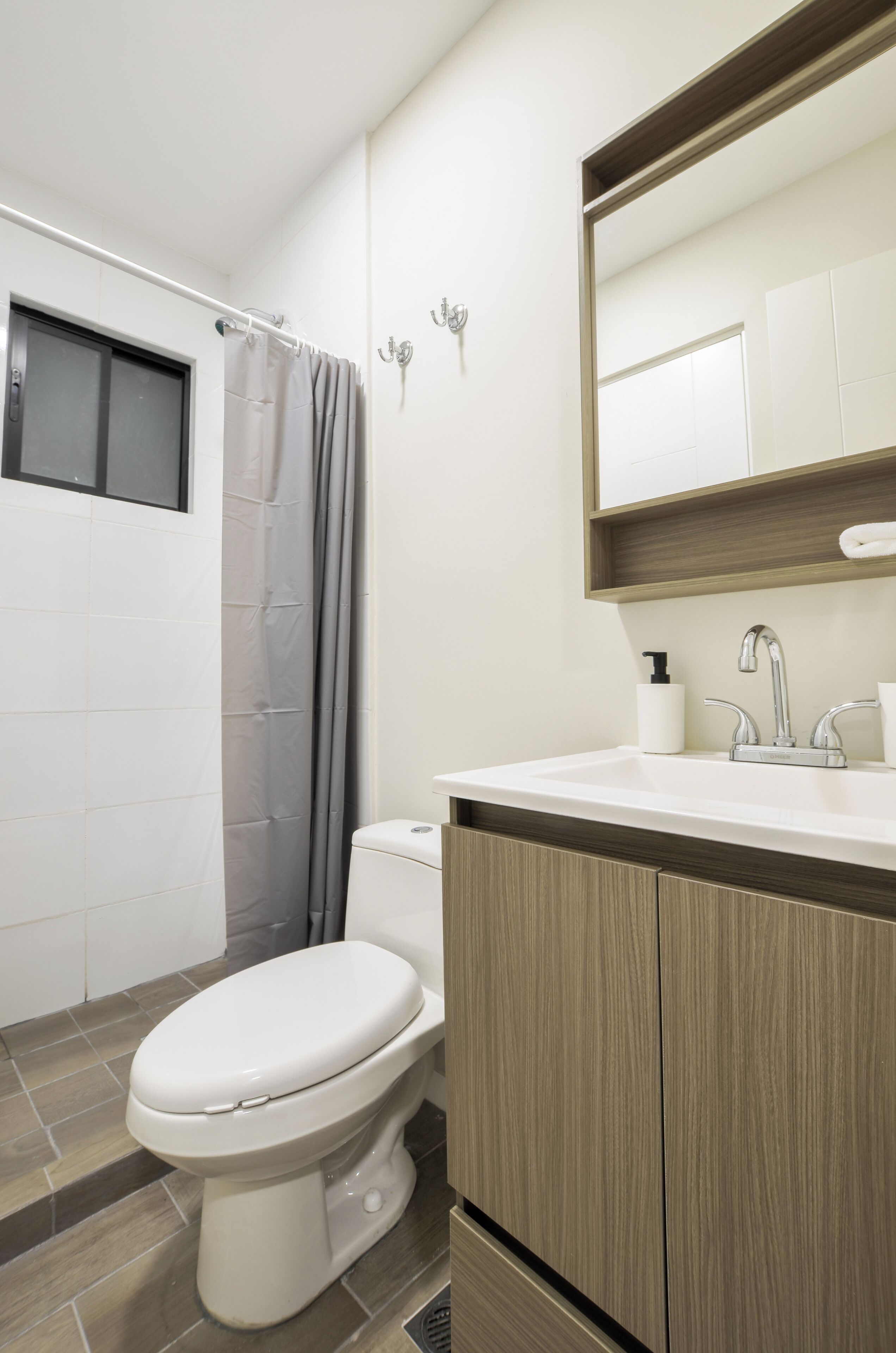 A modern bathroom with a toilet, shower, and sink.