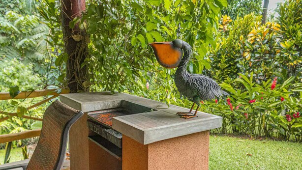 Eine Vogel-Skulptur auf einer Betonkonstruktion mit einem Grill darunter.