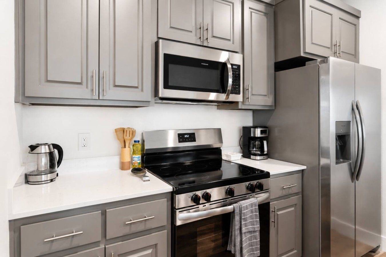 Una cocina moderna con electrodomésticos de acero inoxidable, incluyendo un microondas, horno y refrigerador.