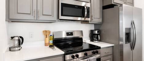 Una cocina moderna con electrodomésticos de acero inoxidable, incluyendo un microondas, horno y refrigerador.