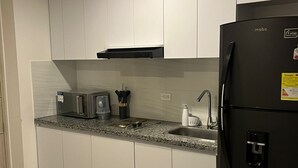 Eine moderne Küche mit weißen Schränken, einem schwarzen Kühlschrank, einer Granit Arbeitsplatte und einem Edelstahlspülbecken.