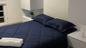 Ein Schlafzimmer mit Bett, Nachttisch und einem Fenster mit Jalousien.