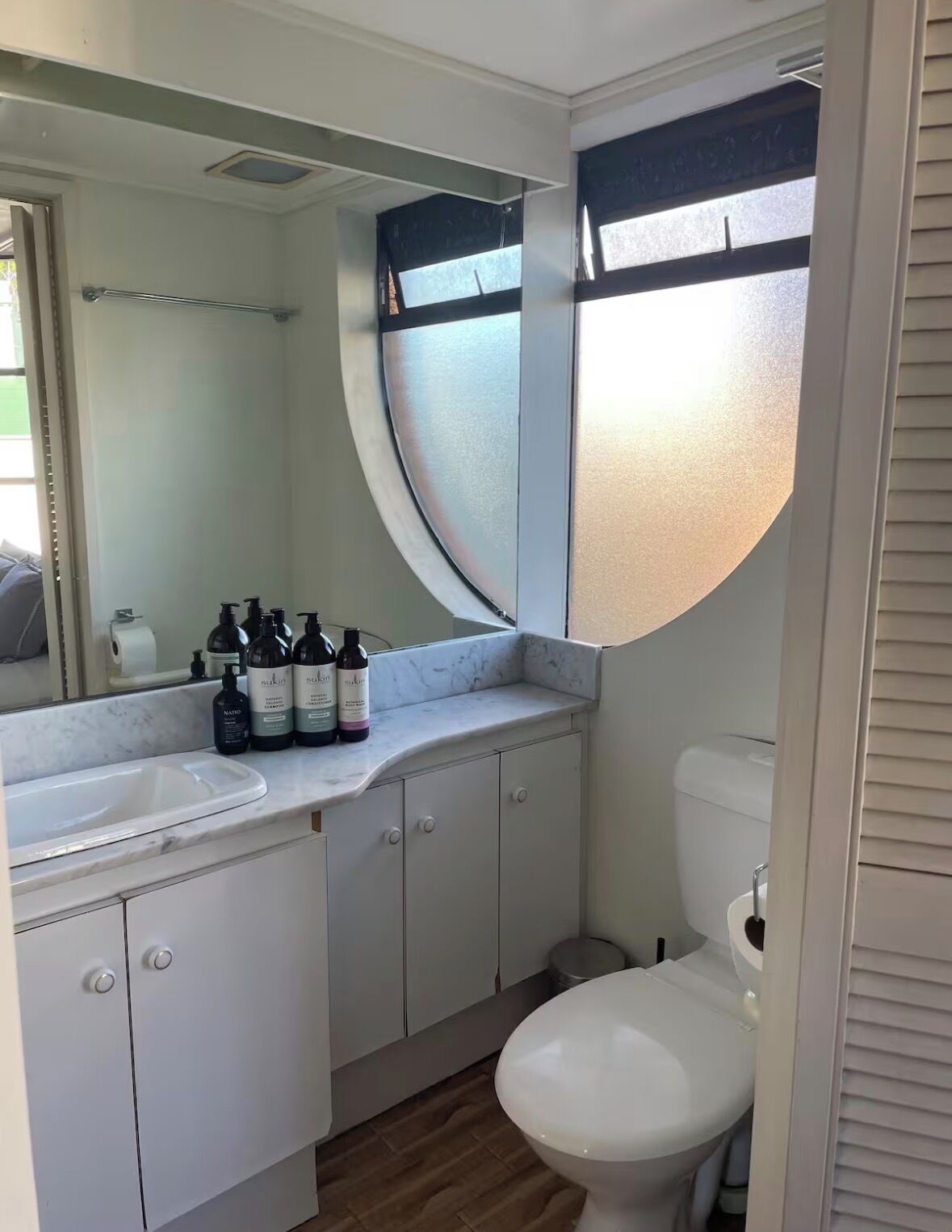 A compact bathroom with a white sink, a mirror, and a toilet.