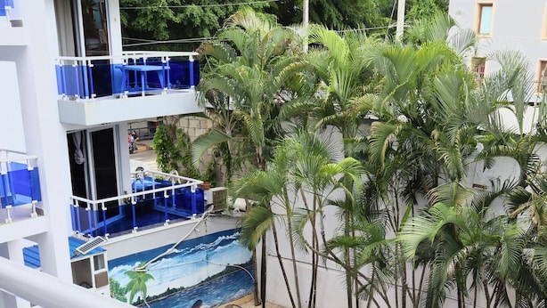 A pool area with multiple levels, palm trees, and outdoor seating. - Immense Splendide Condo Neuf Près de Tout 103 (Sosúa)