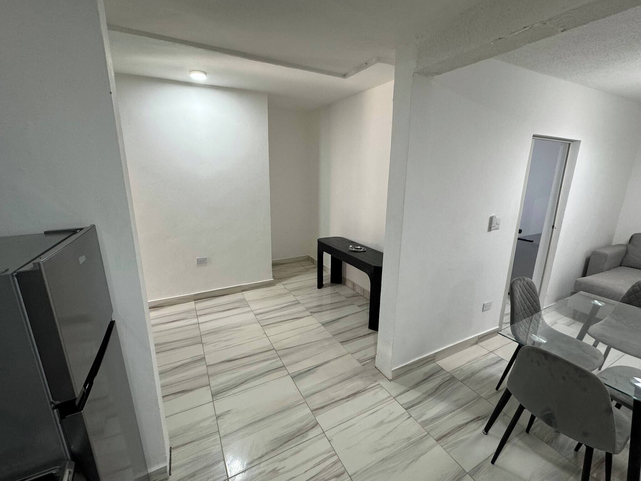 Ein modernes, minimalistisches Wohnzimmer mit Fliesenboden, einem Glastisch und einer Couch.