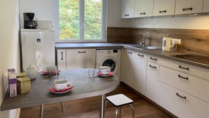 A compact kitchen with a washing machine, a coffee maker, and a sink. - Grand appartement avec jolie vue sur le port de St Cast, 3 chambres pour 6 personnes (ST CAST LE GUILDO)