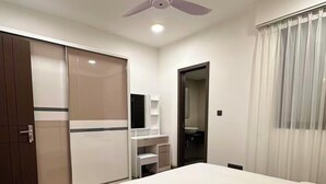 A hotel room with a bed, wardrobe, desk, and ceiling fan. - Luxury 3-bedroom apartment in Hulhumale,Maldives (Malé)