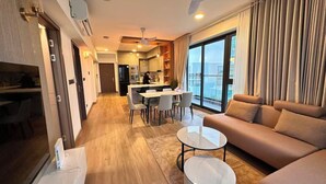 A modern living room with a sofa, two small tables, and a dining area with chairs. - Luxury 3-bedroom apartment in Hulhumale,Maldives (Malé)