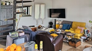 A spacious living room with a high ceiling, a staircase, a flat-screen TV, a sofa, and a coffee table. - Lotf au stes maries de la mer (Saintes-Maries-de-la-Mer)