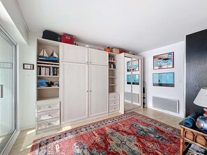 A room with a large wardrobe, a red patterned rug, and a mirror with a bicycle image. - QUIBERON - 2 rooms - 37m2 - Sea View (QUIBERON)