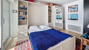 Une chambre à coucher avec un lit, une armoire et une petite table avec une lampe.