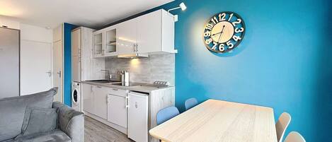 A compact living space with a kitchenette, a dining area, and a sofa.