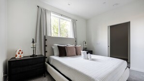 A bedroom with a large bed, a nightstand, a dresser, a window with curtains, and a door. - Cozy Stay Near San Diego With 2 Car Garage (Lemon Grove)